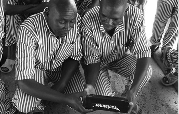 På billedet ses to indsatte, der lytter til en proclaimer på et fællesareal. Foto: De Forenede Bibelselskaber