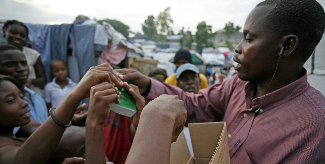 Bibelselskaber over hele verden gør Bibelen tilgængelig gennem nye oversættelser og uddeling af bibler. Her uddeler det haitianske bibelselskab Det Nye Testamente på kreolsk i en flygtningelejr på Haiti. Foto: United Bible Societies.