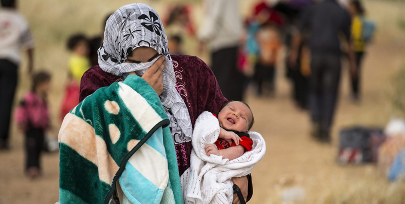 Mor er på flugt fra Syrien med sit barn på armen. Foto: UBS.