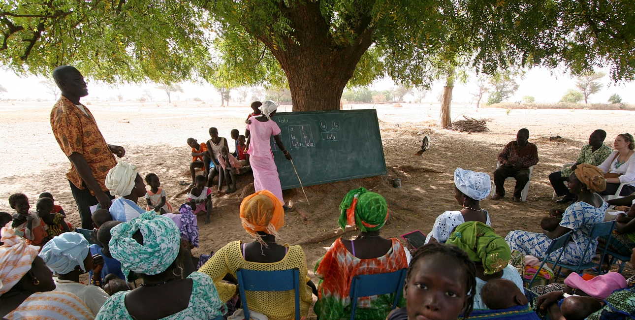 En gruppe mennesker modtager læseundervisning i skyggen i Tattaguine, Senegal. Foto Joaquim Dassonville / UBS. 