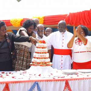 Julekagen skæres for af festdeltagerne. I midten, bag kagen, står Nyombi Peter, som holdt tale efterfølgende. Foto: Bible Society Uganda