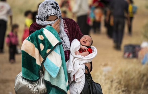 Mor er på flugt fra Syrien med sit barn på armen. Foto: UBS. 