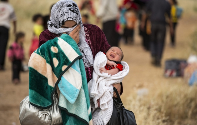 Mor er på flugt fra Syrien med sit barn på armen. Foto: UBS.