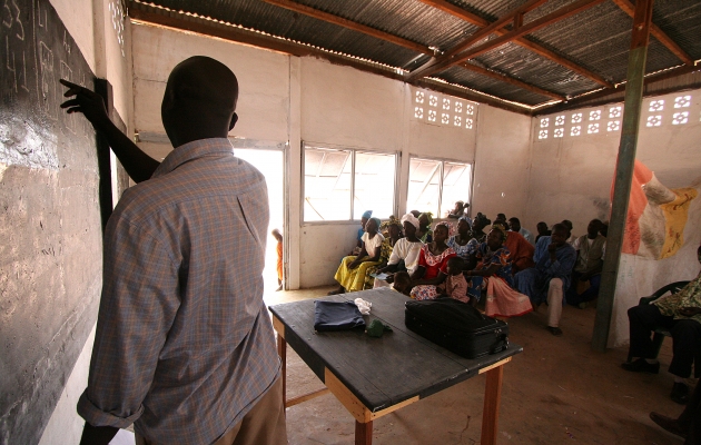 En lærer underviser voksne analfabeter i et køligt lokale i Farabougou. Foto Joaquim Dassonville / UBS. 
