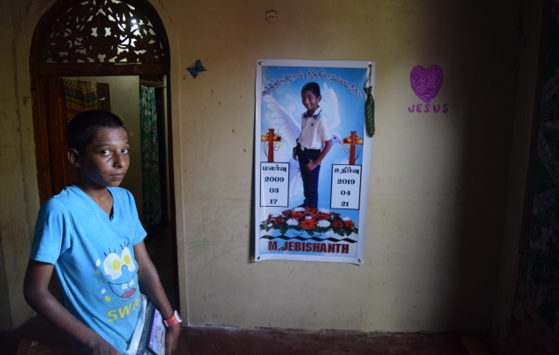 Dreng foran plakat af offer fra Sri Lanka. Foto: Sri lankas Bibelselskab